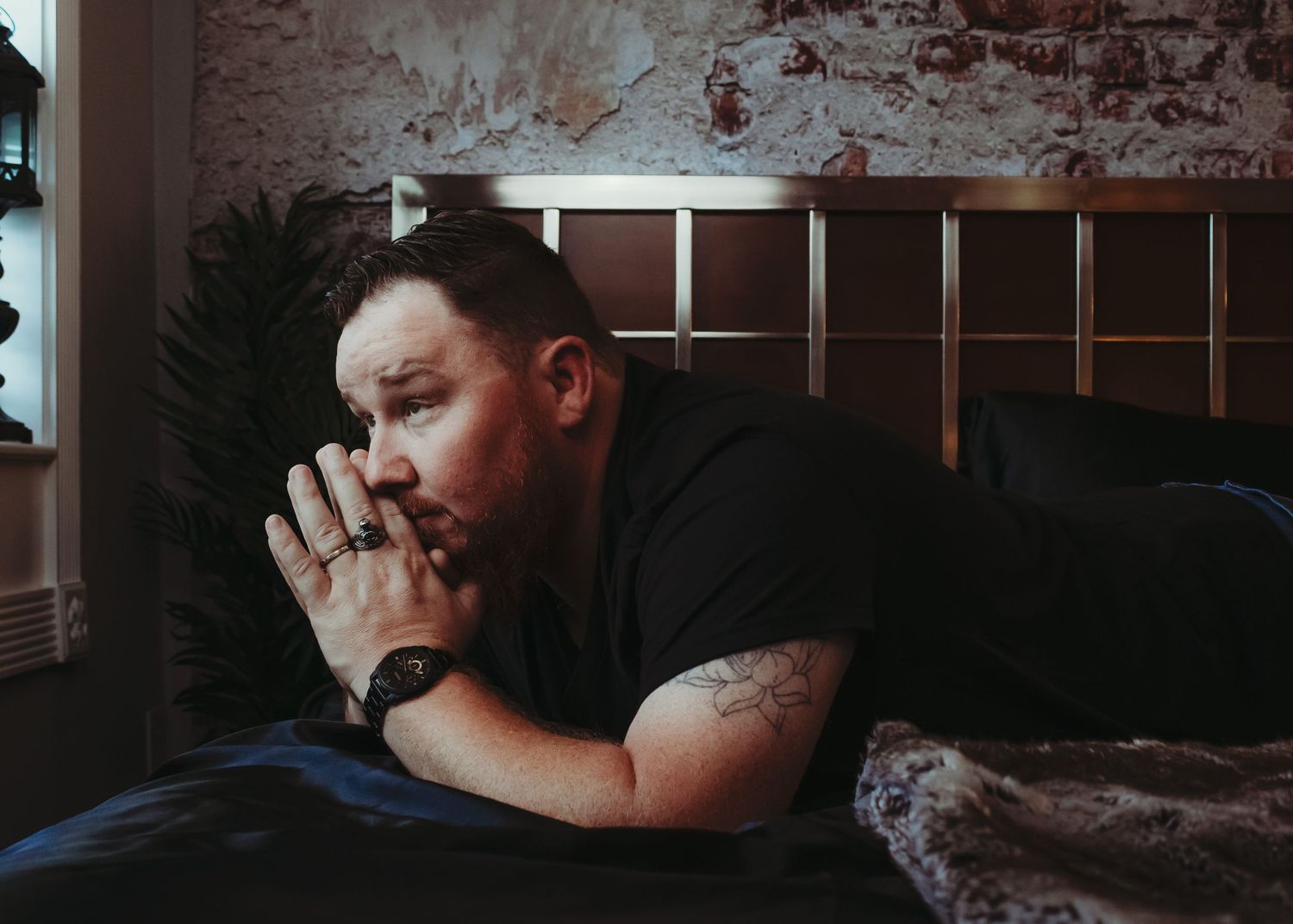 Dark moody boudoir photography with exposed brick wall.