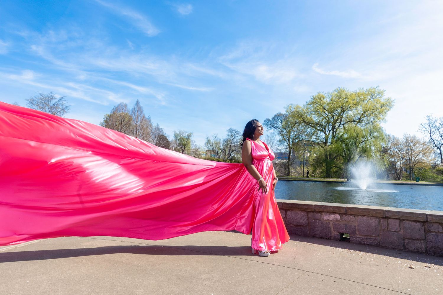 A group poses in vibrant flowing dresses of pink, green, red, blue and purple against a bright sky.