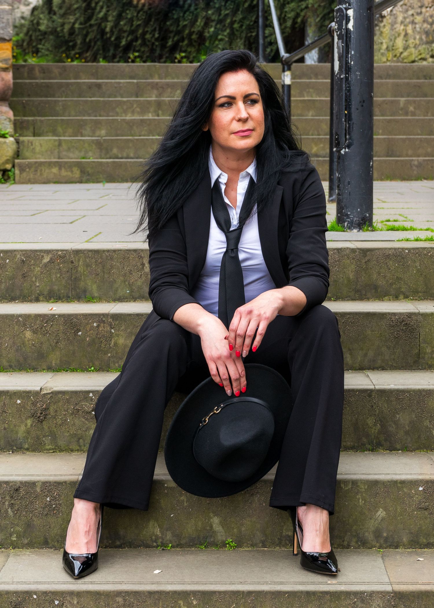 Figure in business attire sits casually on outdoor stone steps.