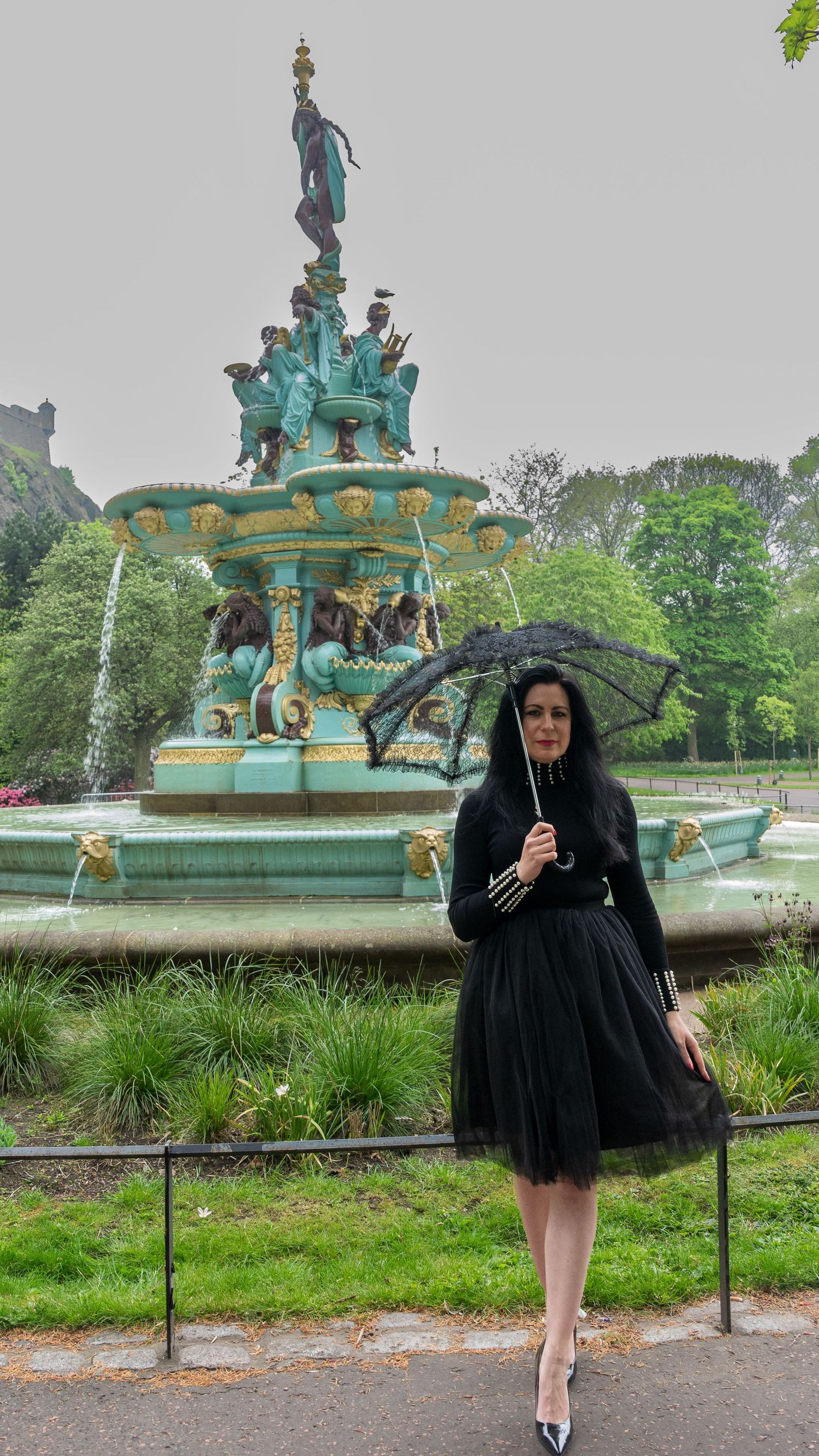 A decorative turquoise fountain in an Edinburgh park setting with greenery in the background.