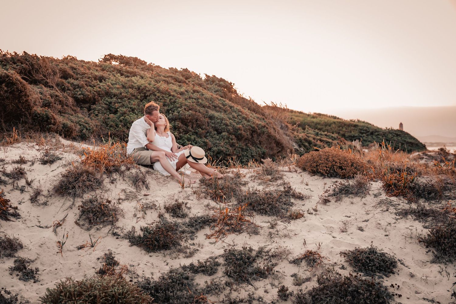 Romantic couple sitting in coastaal sand during a Mallorca beach engagement photoshoot.