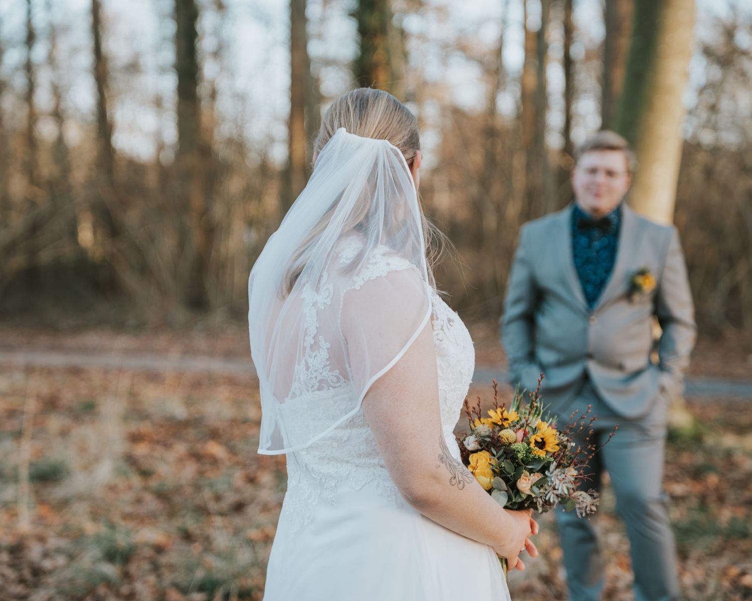 Wedding couple embracing in an autumn forest setting with fallen leaves.