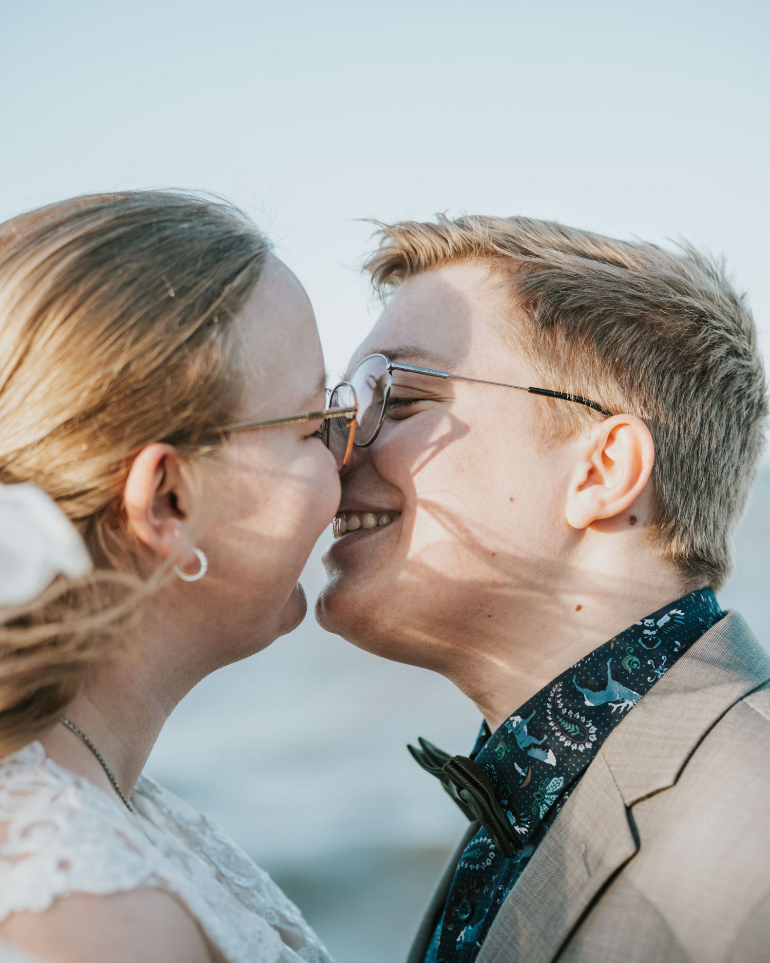 Romantic couple sharing an intimate moment against a soft blue sky background.