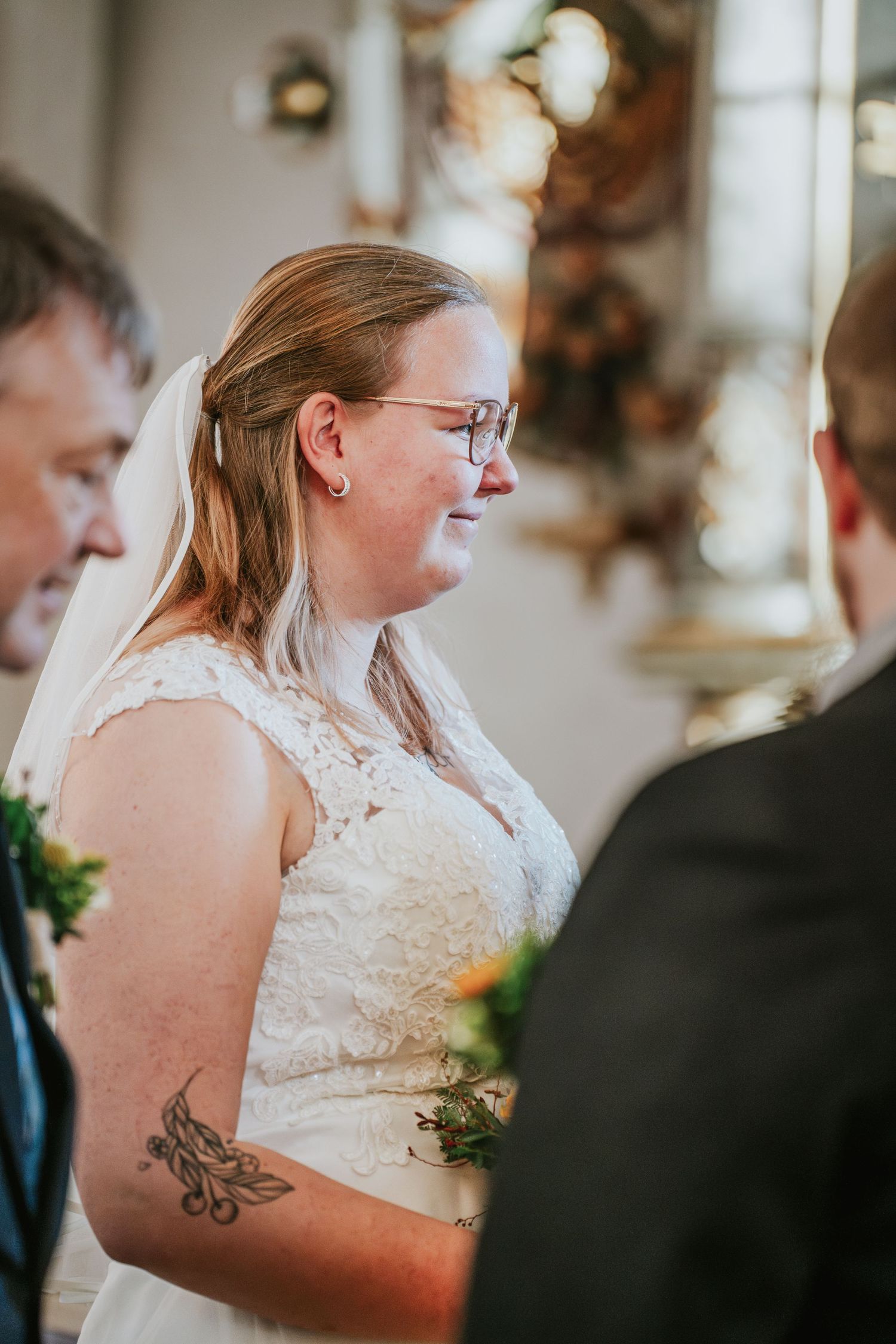 Close-up details of a bride in lace dress during church ceremony.
