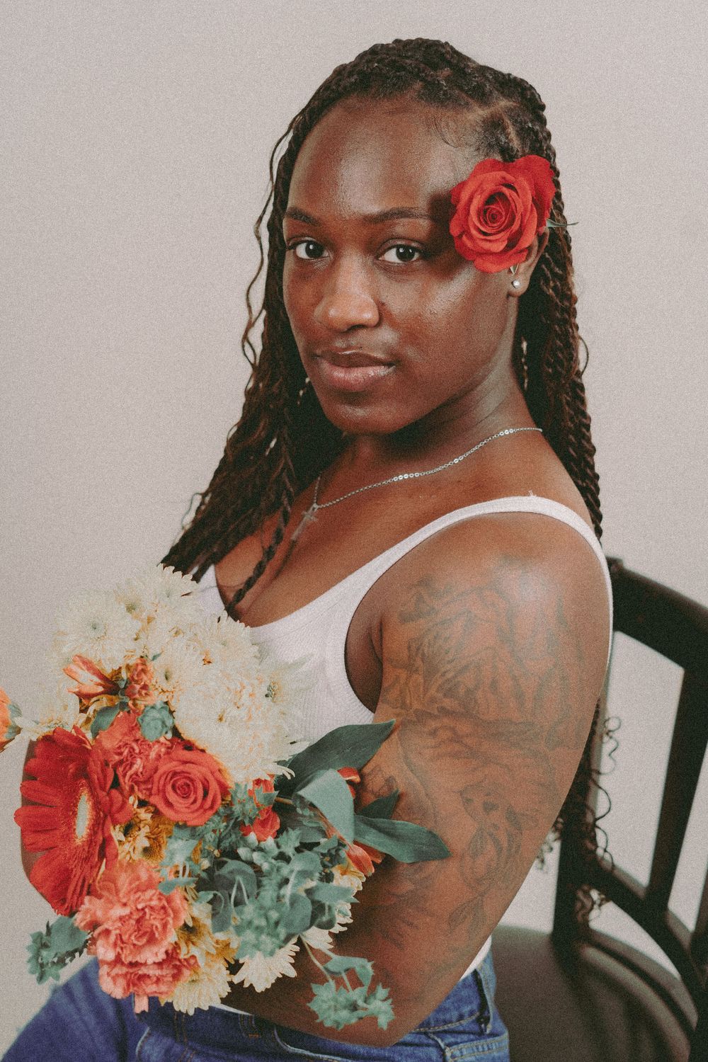 Person with braids holds colorful bouquet of roses and flowers in artistic portrait session.