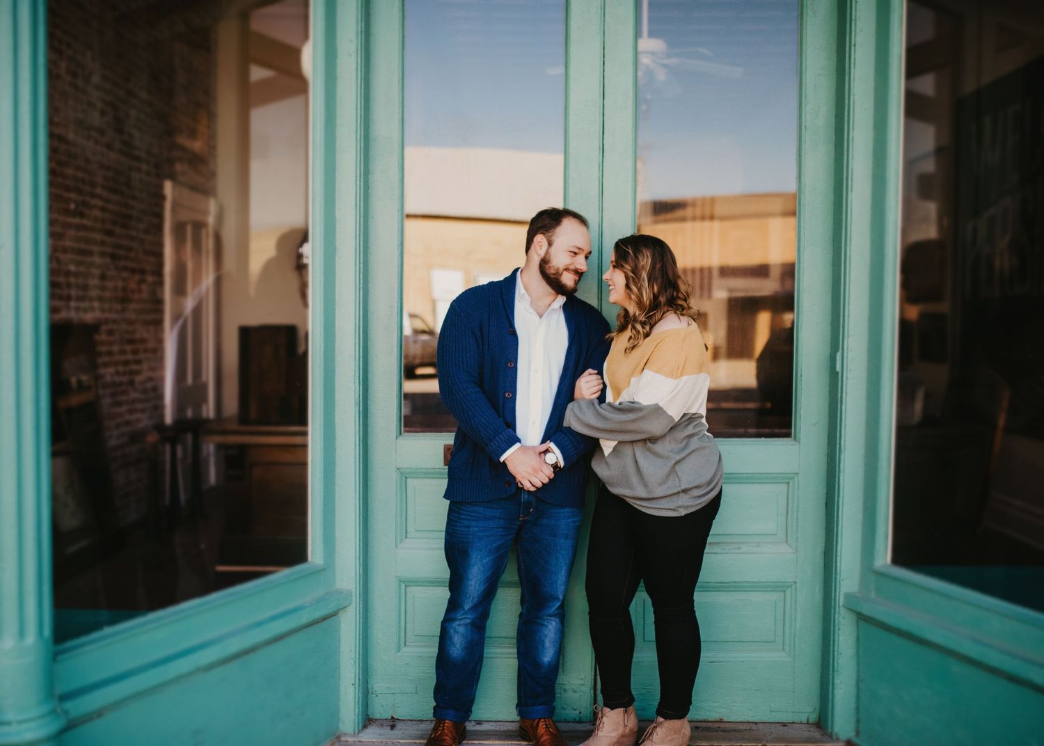 "Newly Engaged couple standing in front of Green Doors."