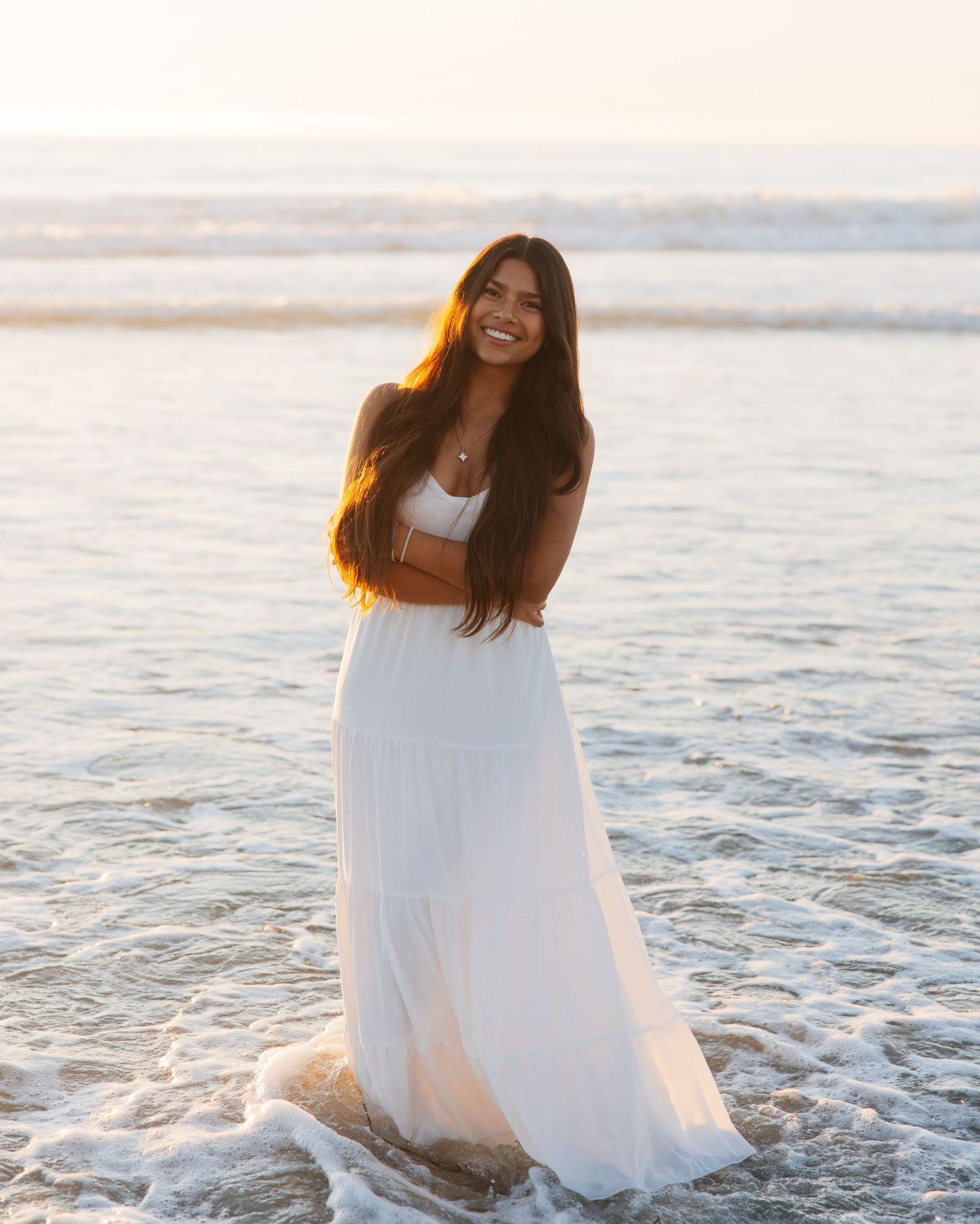 Person in white dress twirling and posing in sunny field of yellow flowers.