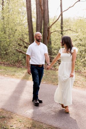 A couple takes a romantic stroll along a tree-lined path.