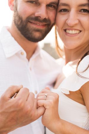 Close-up portrait of a couple showing their engagement rings.