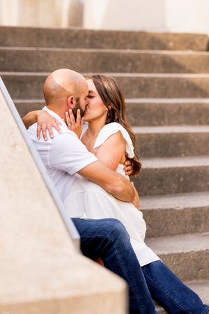 A romantic moment shared on concrete steps during an engagement photoshoot.