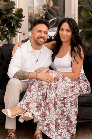 Couple in white and floral outfits share intimate moments on outdoor furniture.