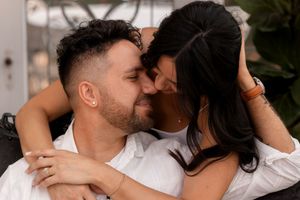 Loving couple embraces while sitting in a garden setting during a photo session.