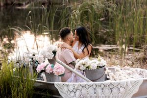 Couple poses in rustic boat surrounded by tall grass during sunset photo session.