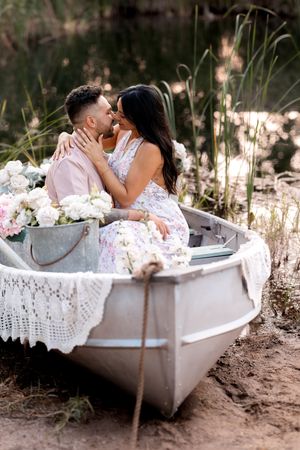 Intimate couple's photo shoot in decorative white boat with floral arrangements.