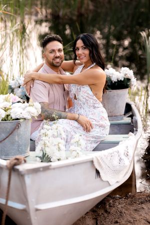 A romantic outdoor photoshoot featuring a white clawfoot bathtub decorated with flowers in a natural setting.