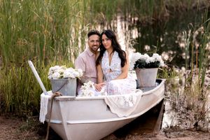 Couple poses together in a vintage white bathtub surrounded by greenery during an outdoor photoshoot.