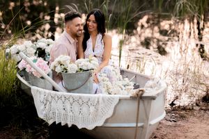 Artistic engagement photos taken in a decorative white bathtub with lace details outdoors.