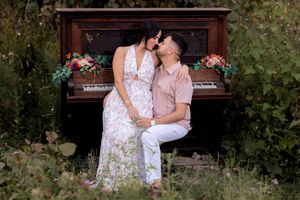 Romantic portraits taken by a vintage piano decorated with flowers in an outdoor garden setting.
