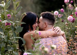 Intimate moment captured among blooming pink roses during an outdoor photoshoot.