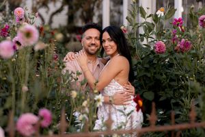 A romantic photoshoot in a garden with pink flowers and natural sunlight creating a dreamy atmosphere.