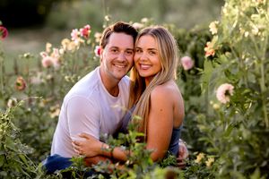 A couple shares an intimate moment among blooming pink flowers in a garden.