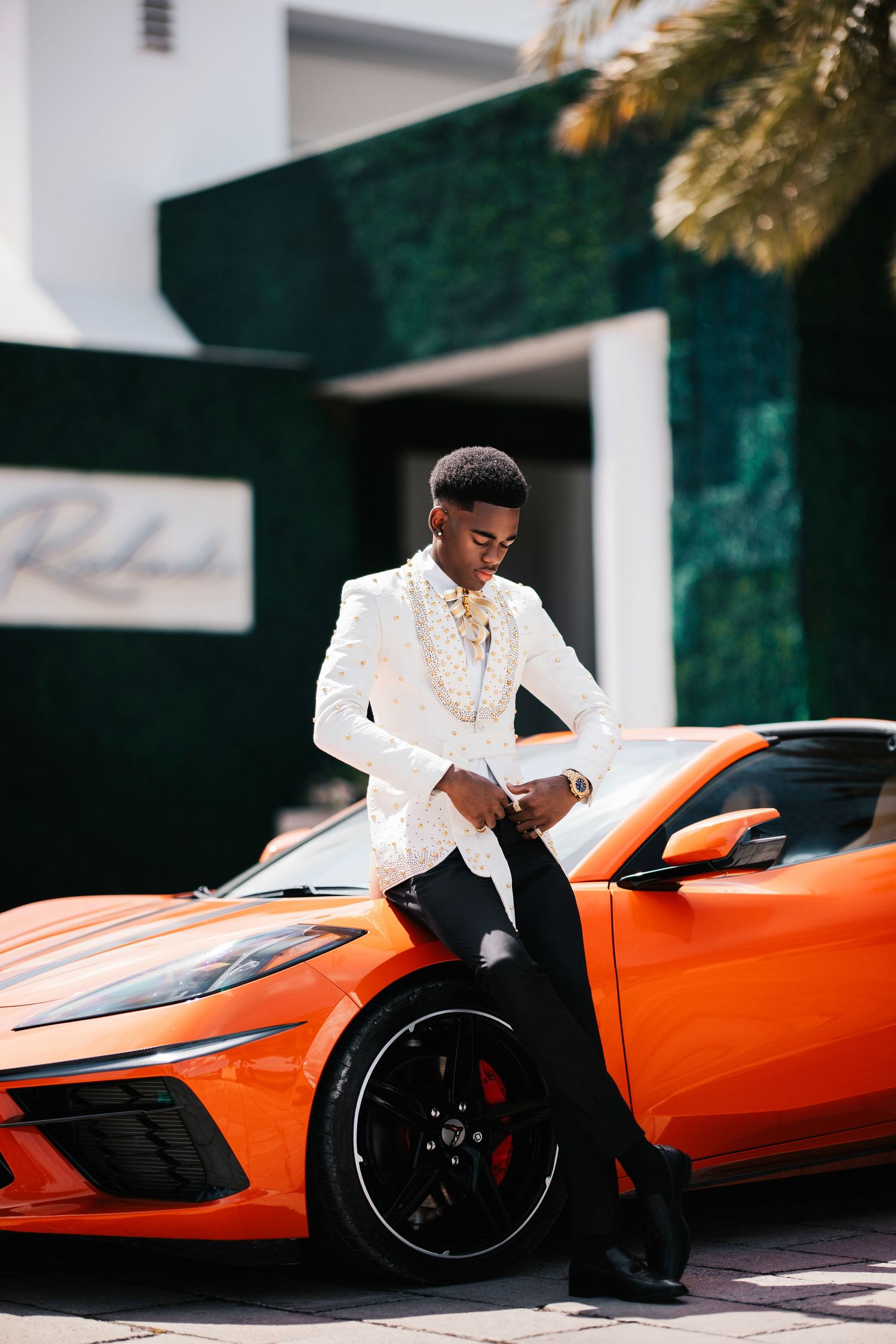 Stylish portrait session with orange McLaren sports car in white formal attire.