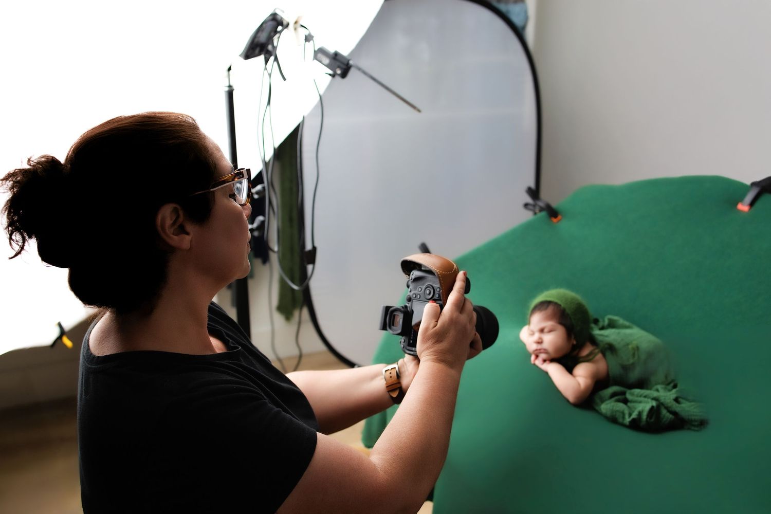 Black and white photo of newborn positioning session with soft fabric backdrop.