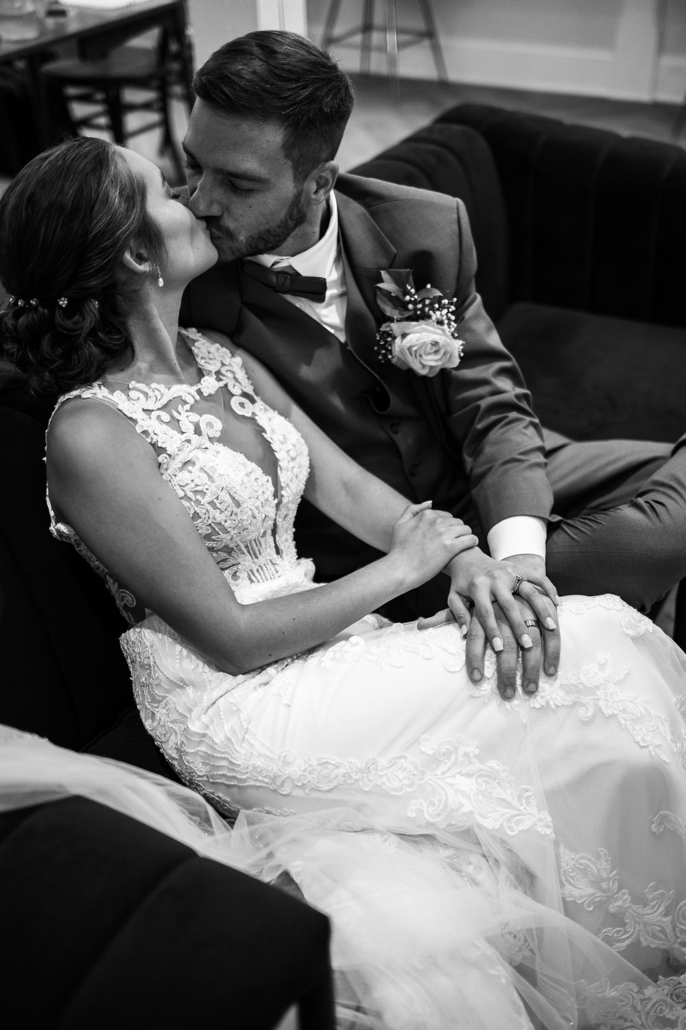 Intimate black and white portrait of newlyweds sharing a romantic moment on a couch.