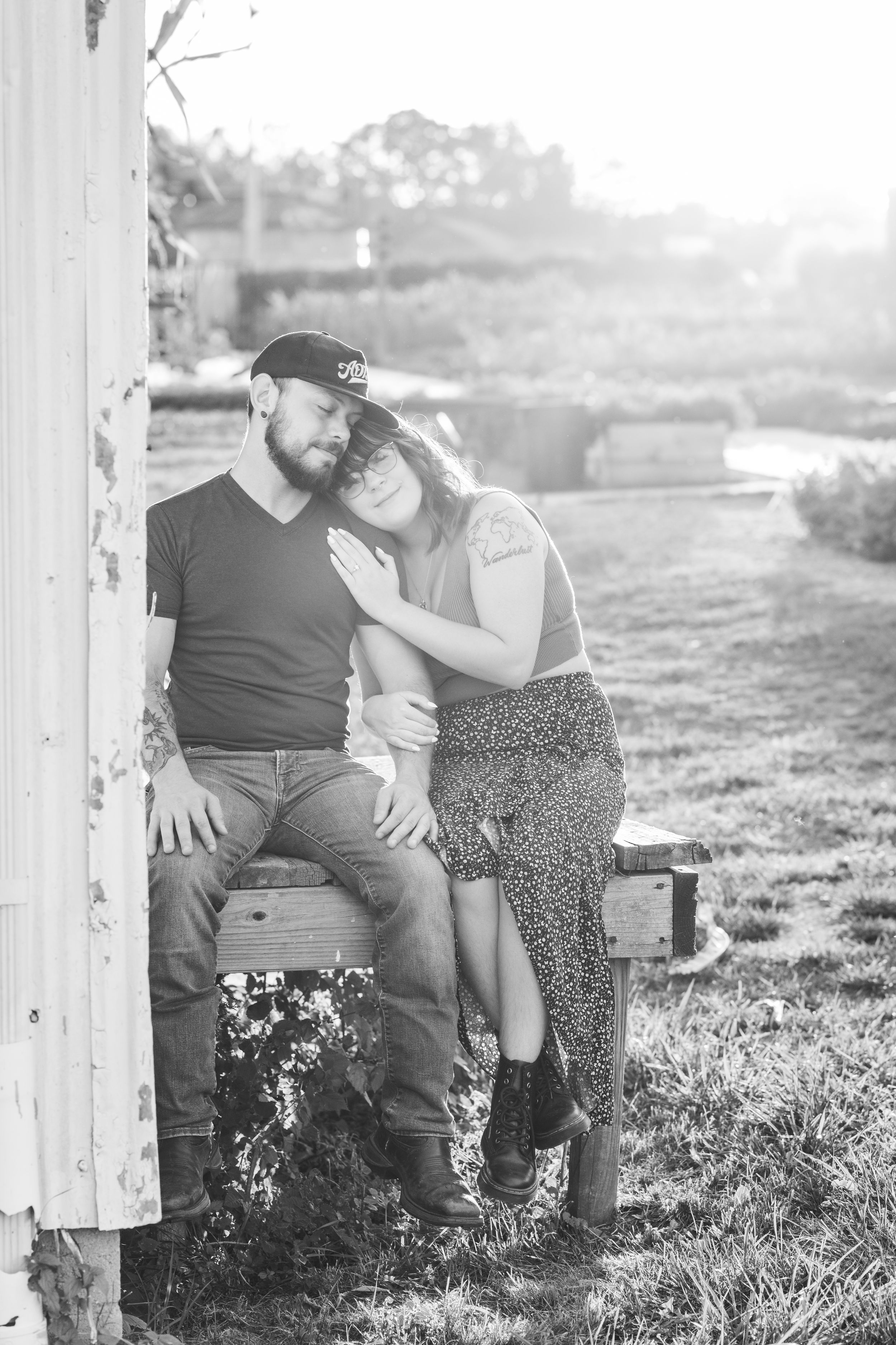 A romantic black and white portrait of a couple sharing an intimate moment against a rustic outdoor backdrop.