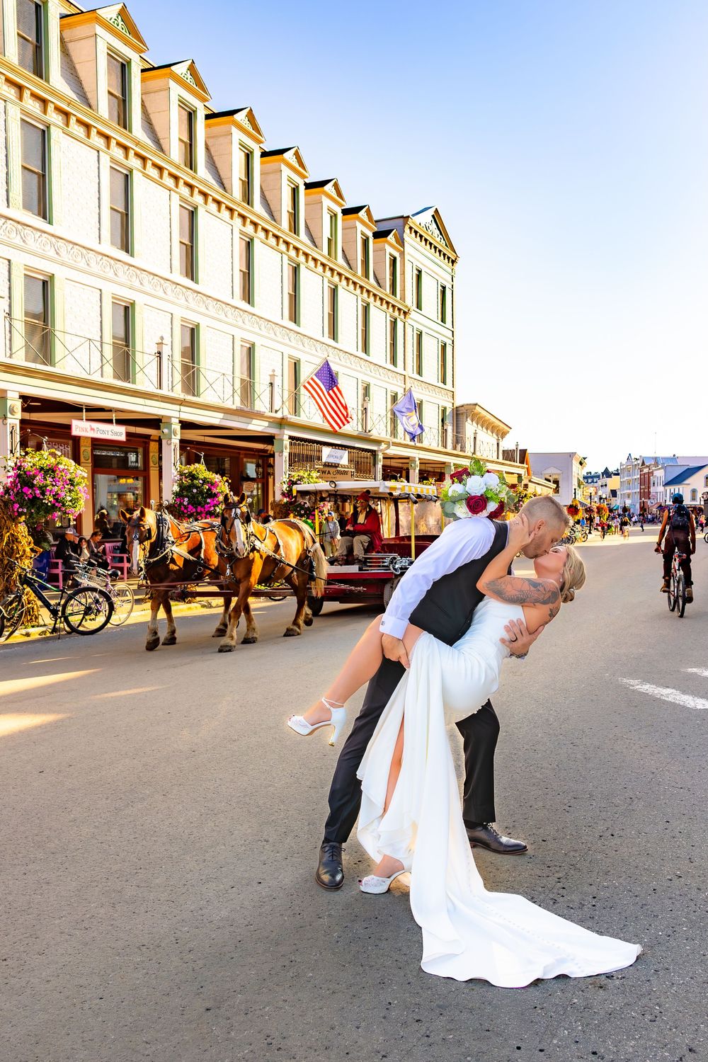 A romantic dip kiss sequence on Mackinac Island's Main Street with a wedding couple surrounded by bicycles and shops.