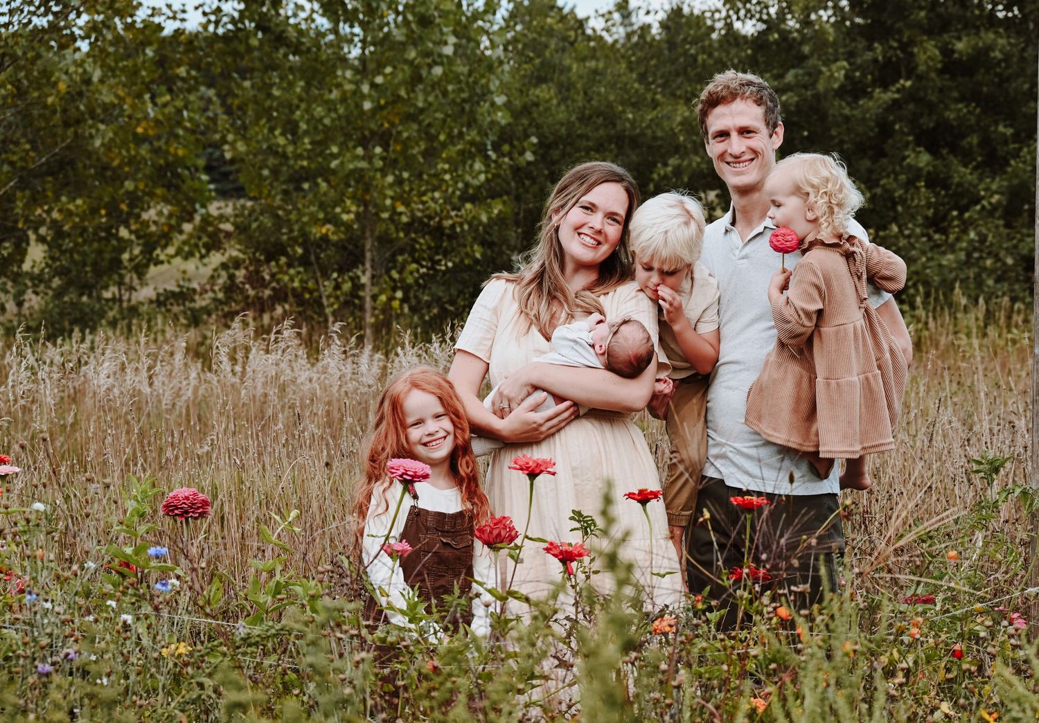 A loving family shares joyful moments together in a sunlit wildflower meadow during a summer photo session.