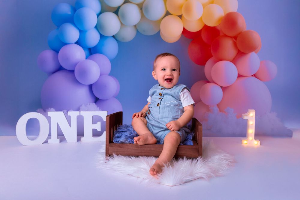 A collection of baby birthday photos with soft balloon decorations in blue and purple tones against a dreamy backdrop.
