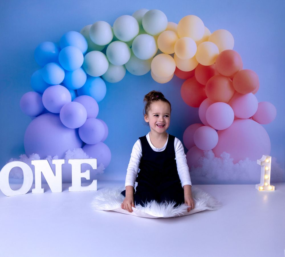 Pastel balloon garland with pink and blue gradient creates a dreamy backdrop for a first birthday celebration setup.