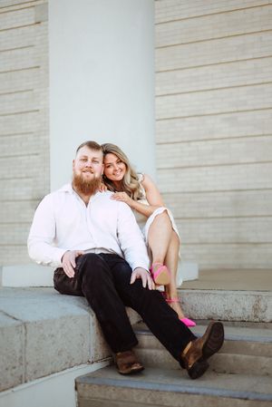 Couple relaxes on stone steps of a building during an intimate photo session.
