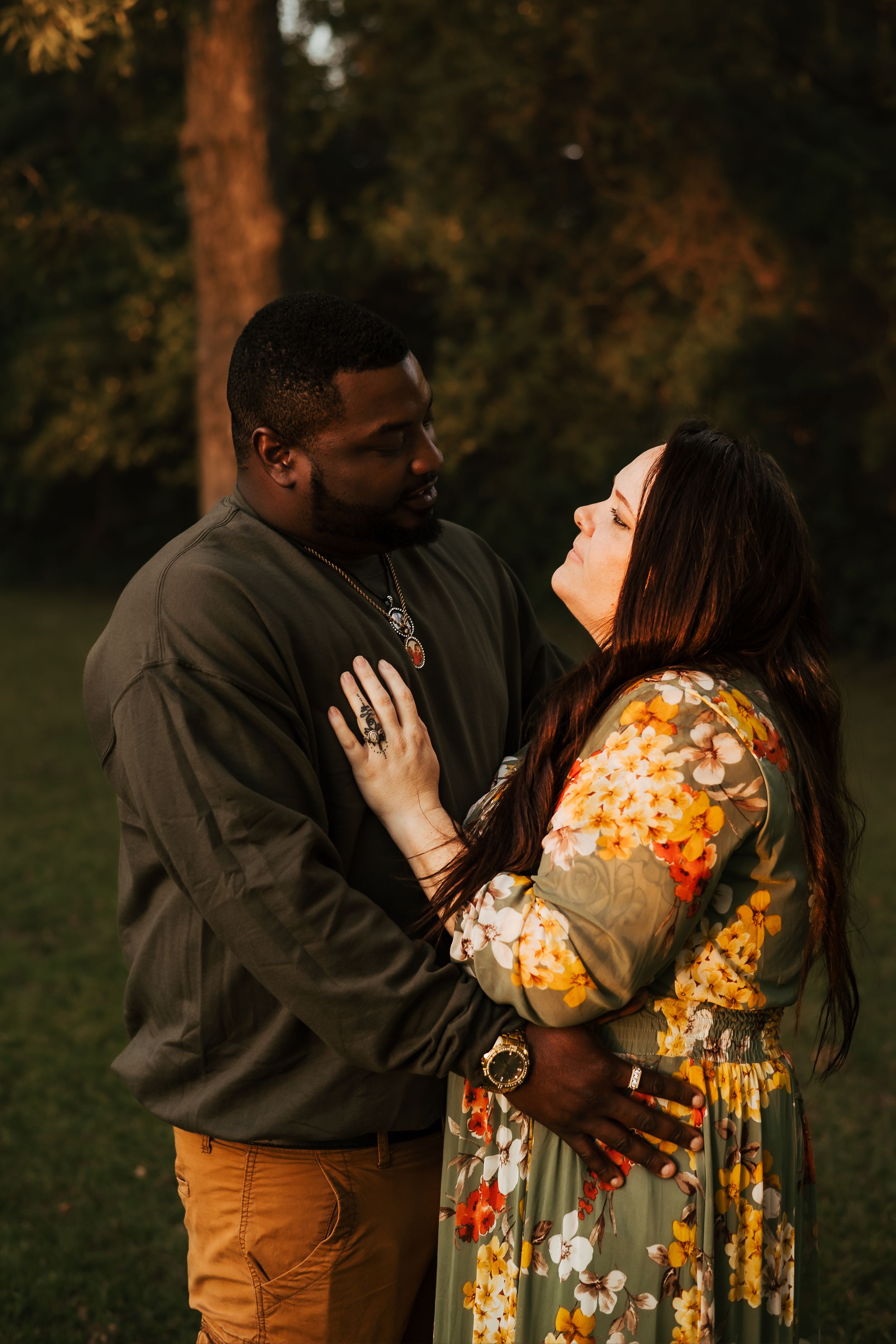 A couple shares an intimate moment at sunset in a garden setting.