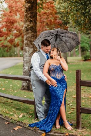 A couple shares a romantic moment under a black lace umbrella on a rainy autumn day.