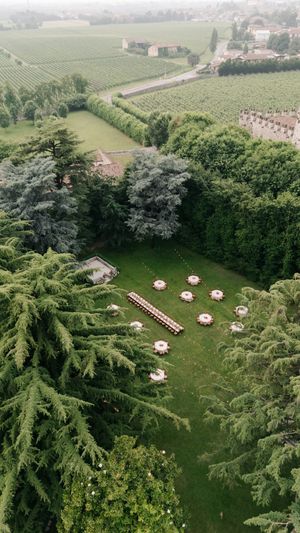 Aerial view of a lush garden venue with white umbrellas and tables set up for outdoor dining or events.