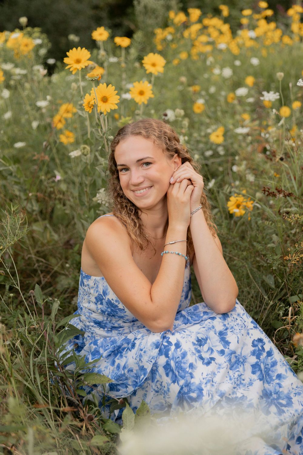 teenage girl sitting in a field of wildflowers at a park in Oakland county michigan