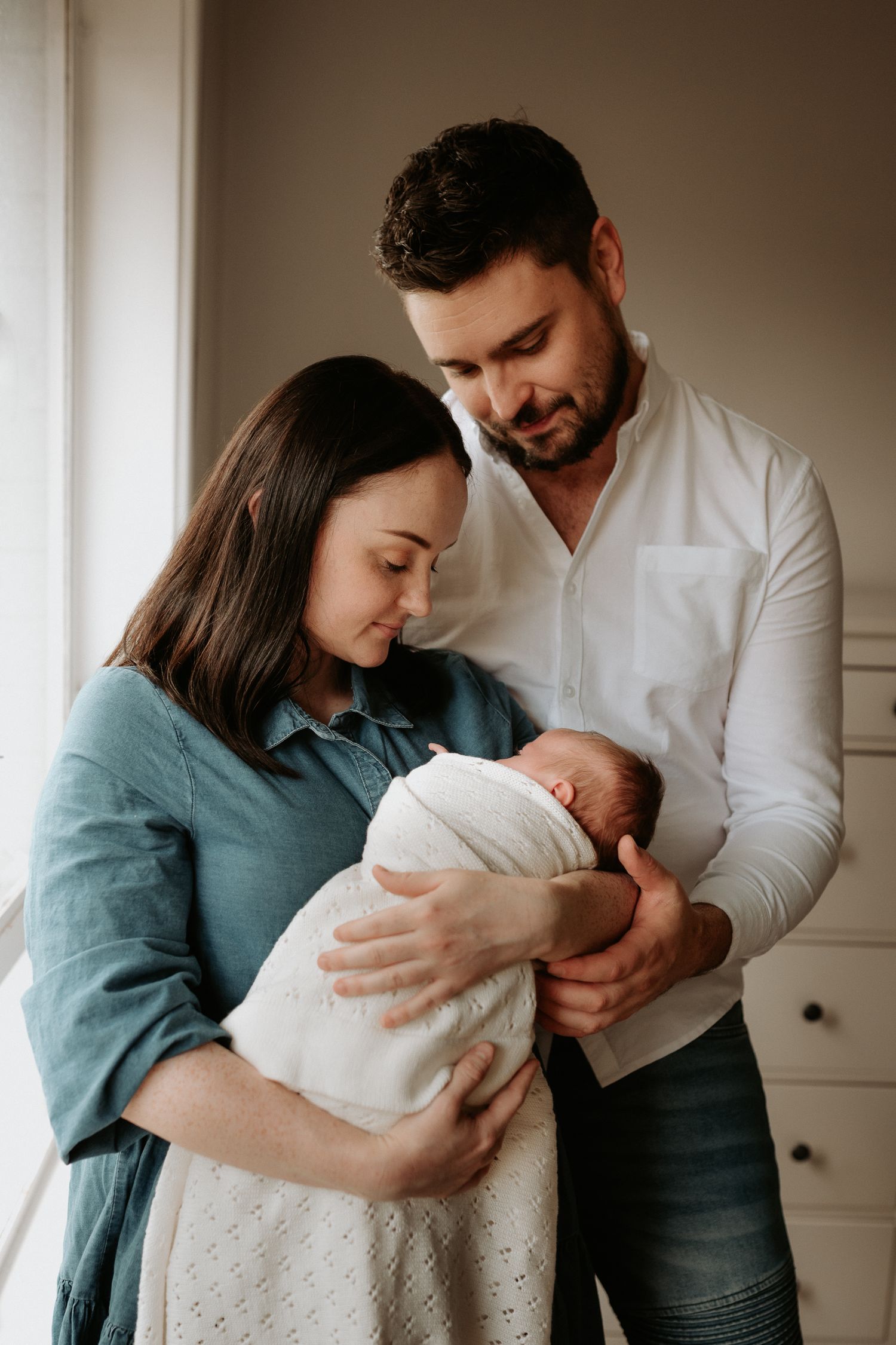 Series of tender family moments with newborn in white and teal tones.