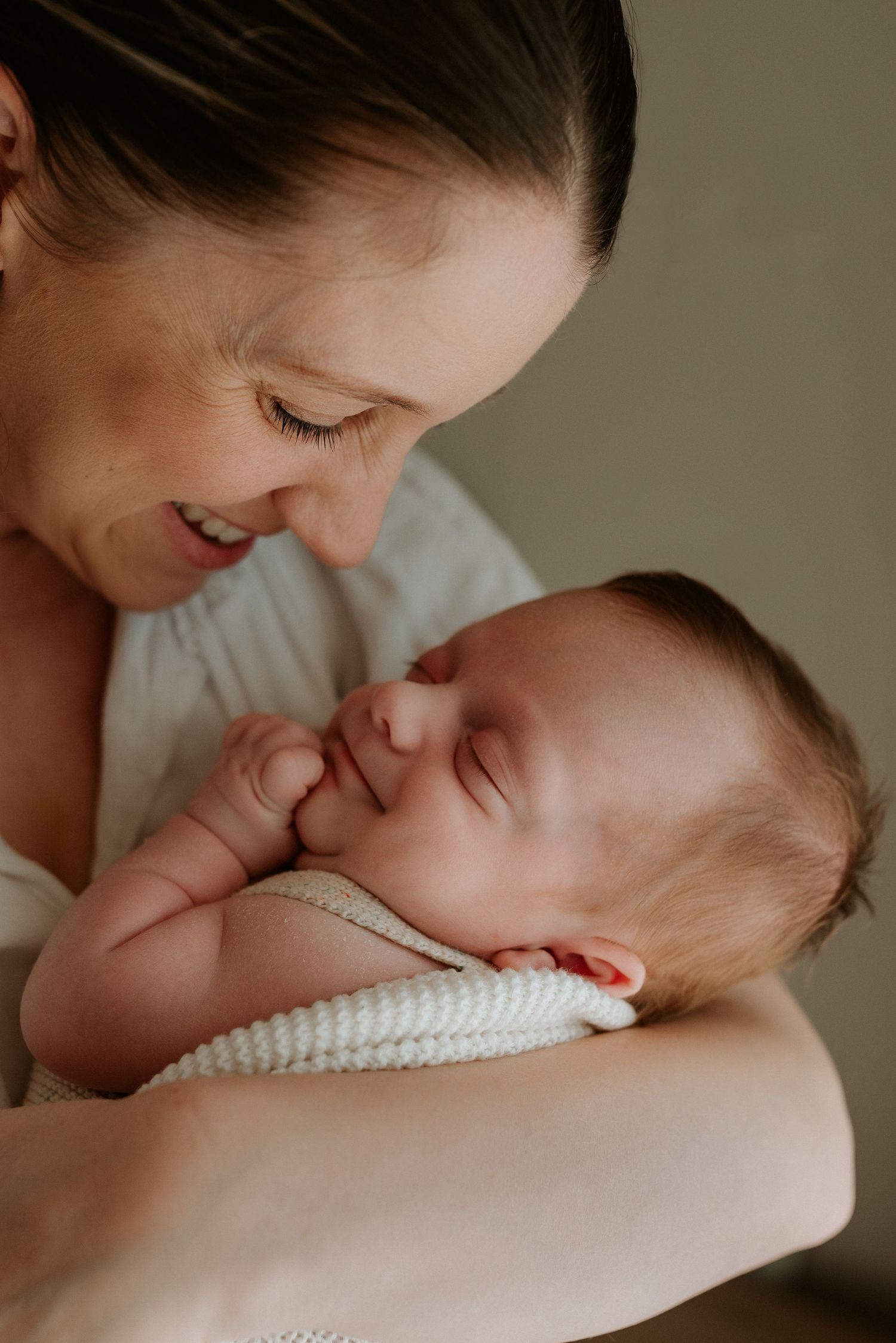 Close-up shots of tender moments with a sleeping newborn wrapped in white.