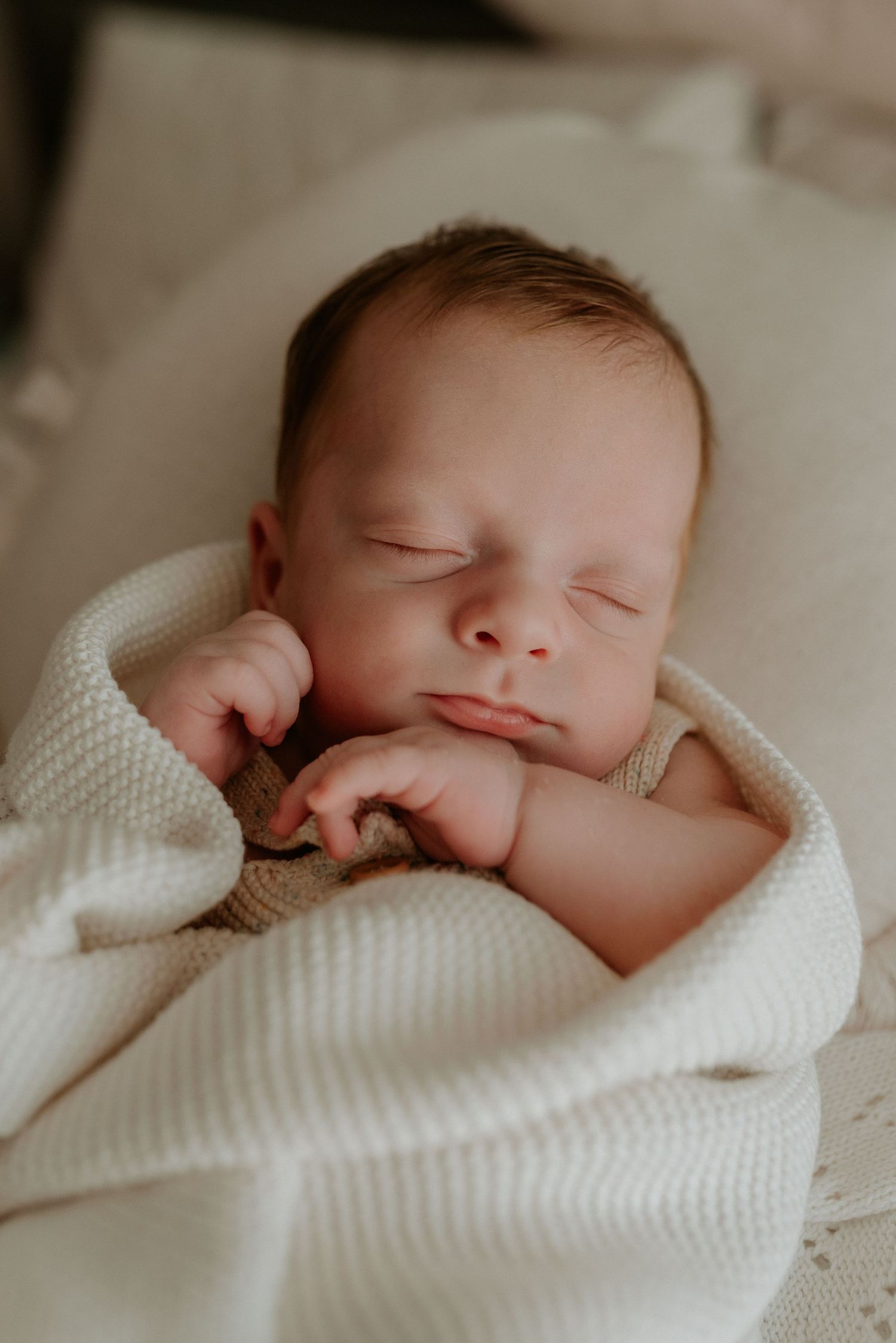 Peaceful newborn sleeping soundly wrapped in a white textured blanket.