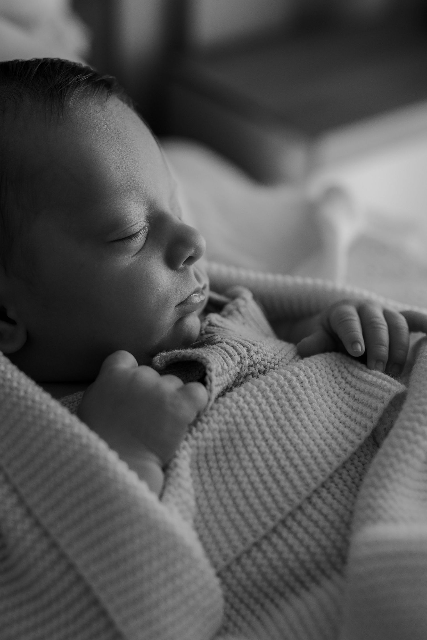 Black and white portrait series of a sleeping newborn in soft lighting.