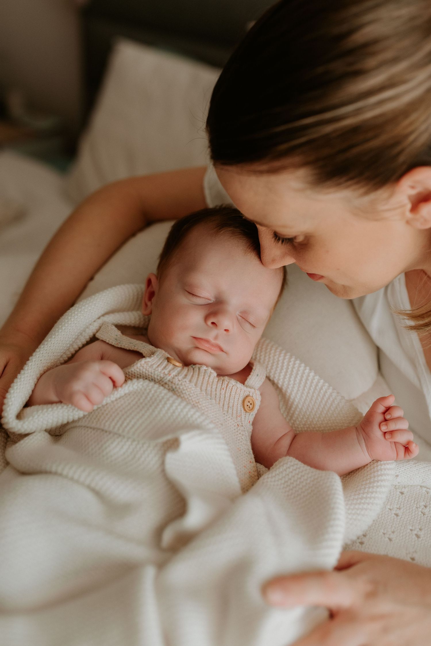 Intimate moments of a sleeping newborn in white knit clothing.