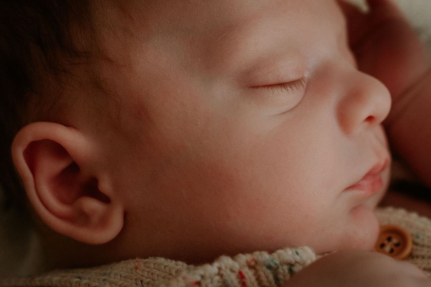 Close-up details of a sleeping baby's facial features in natural lighting.