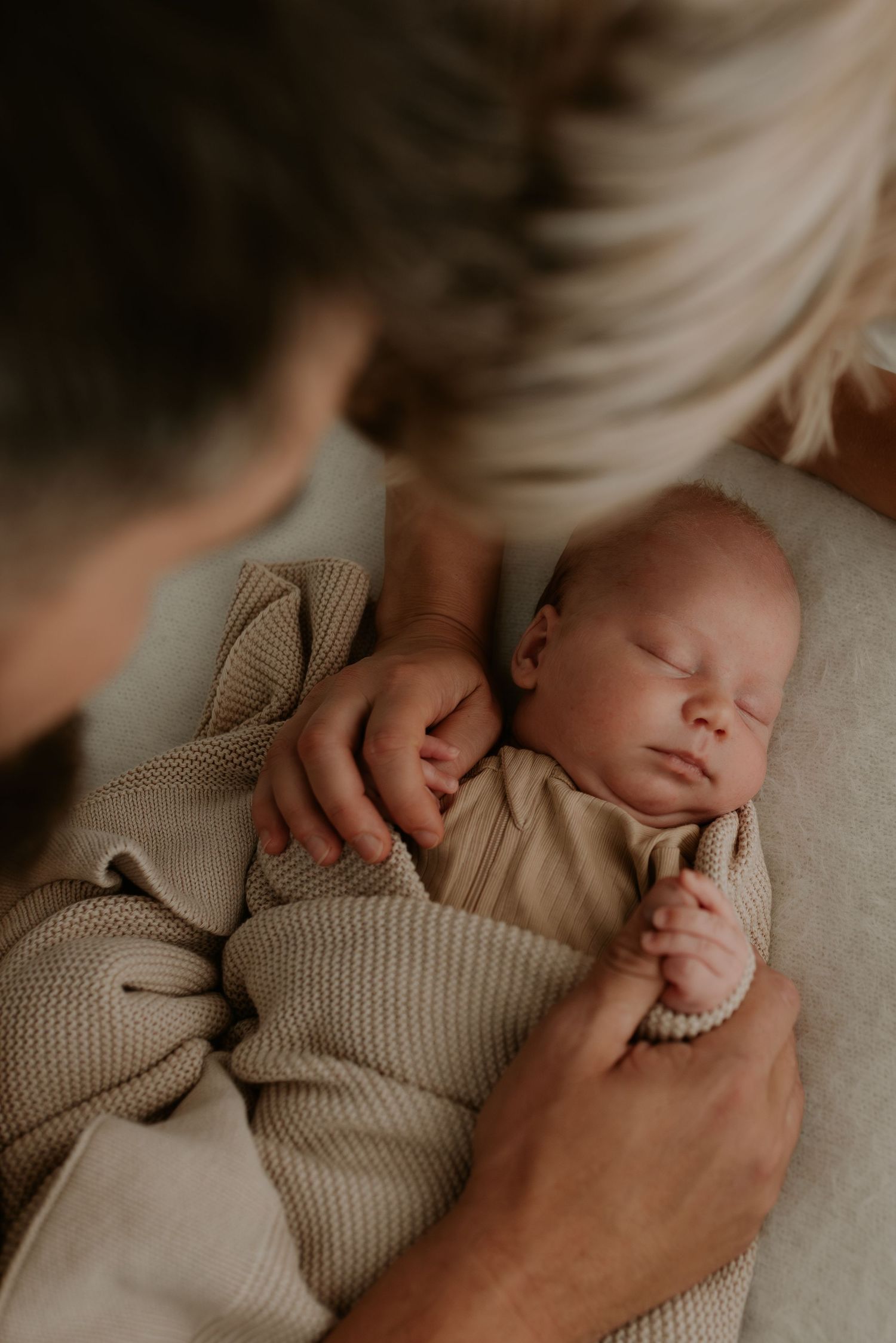 Peaceful sleeping infant wrapped in cozy beige knit sweater.
