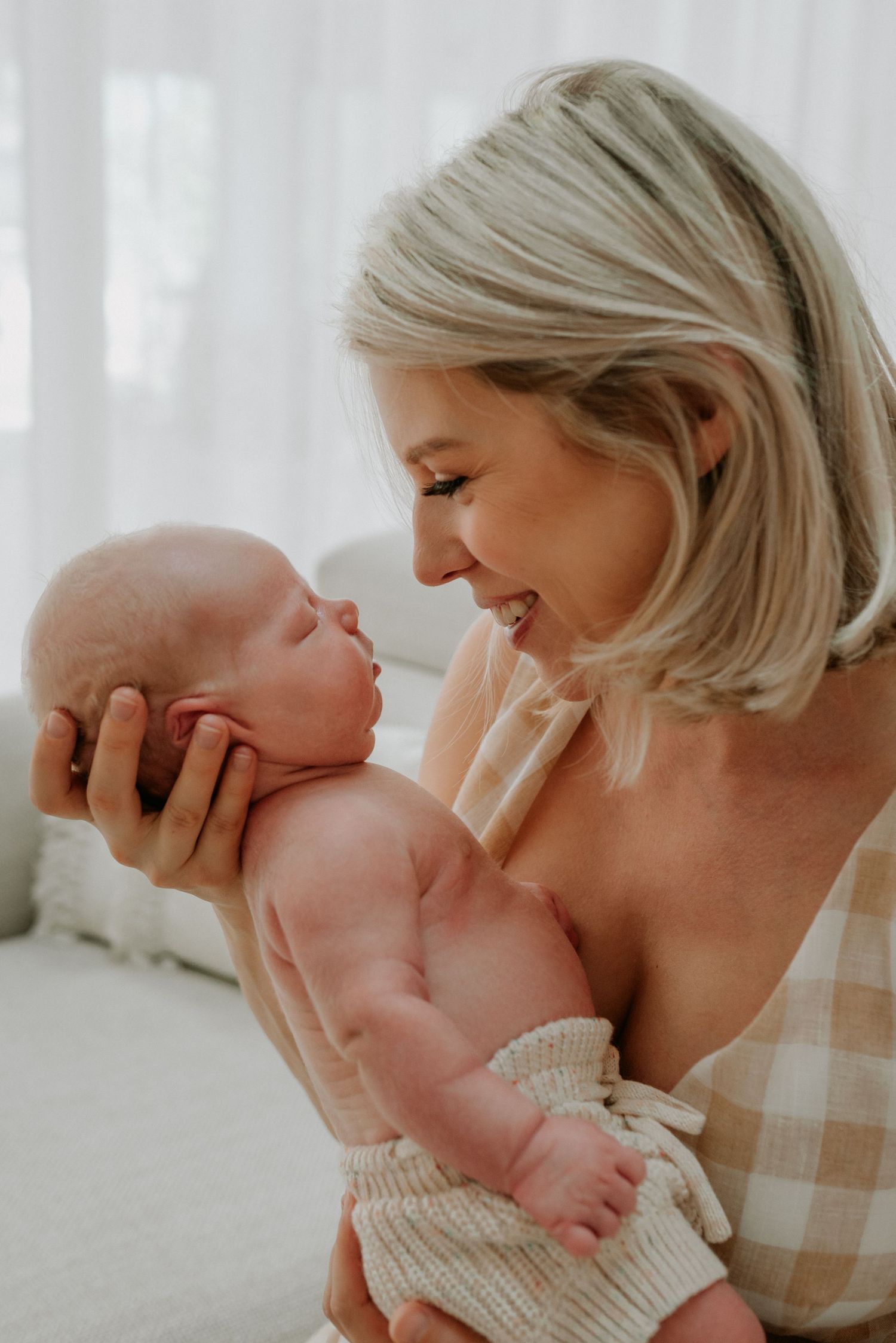 Joyful moment shared between parent and baby in bright sunlit room.
