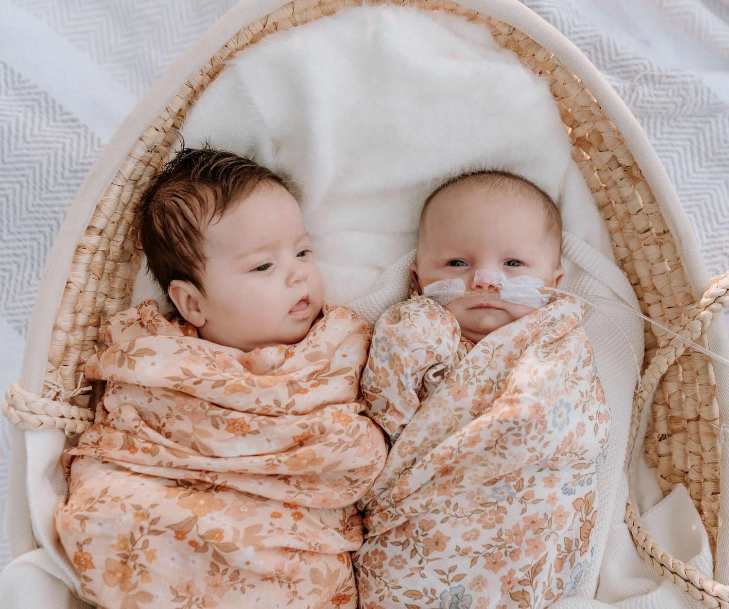 Series of newborn twins nestled together in matching peach floral swaddles.