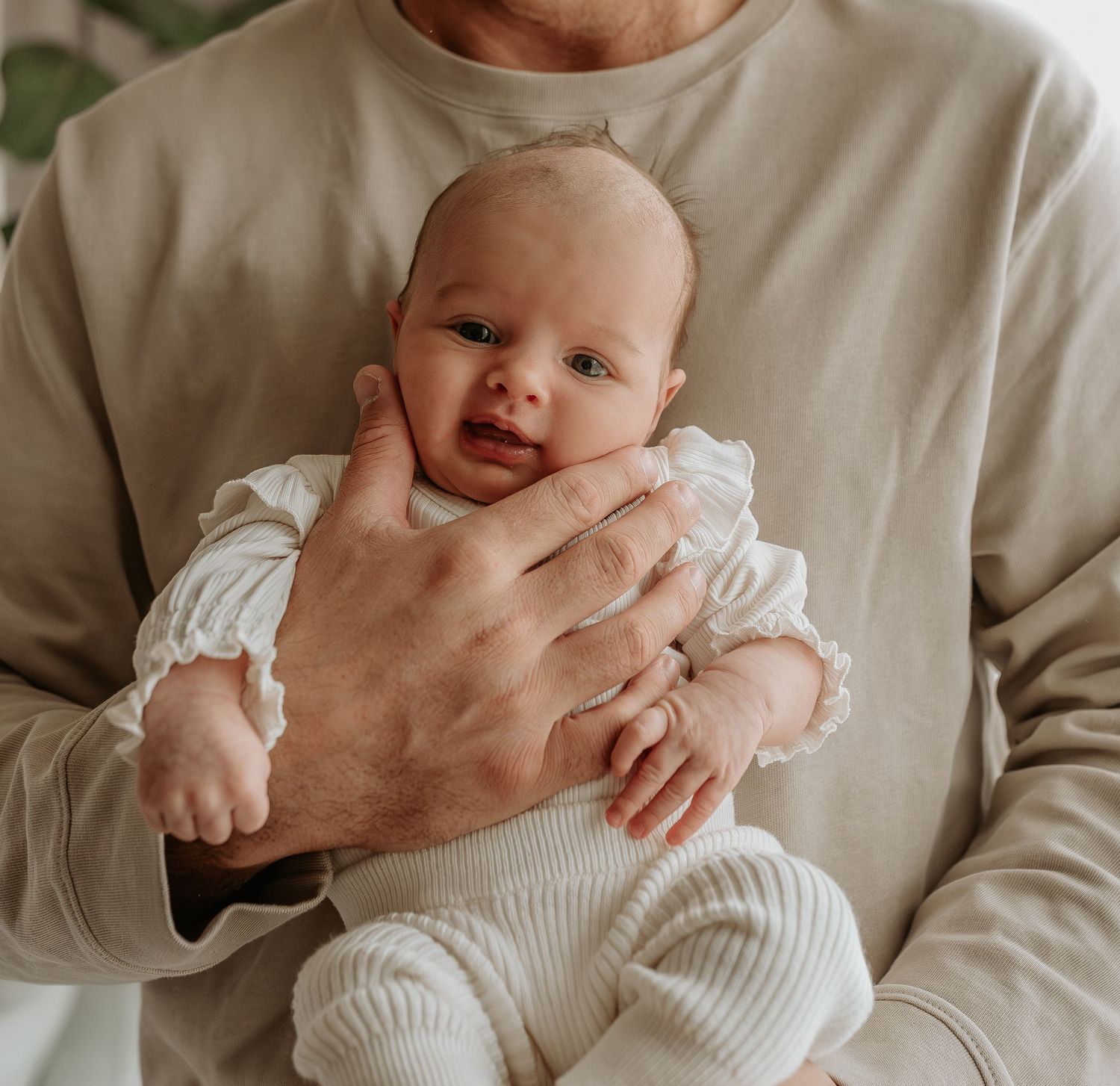 A series of tender close-up shots showing gentle interactions with a baby wearing white.