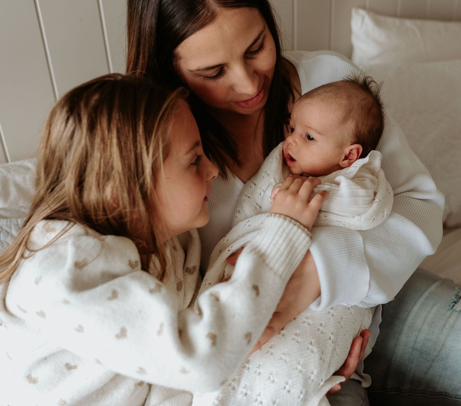 Intimate moments captured between family members in soft white sweaters.