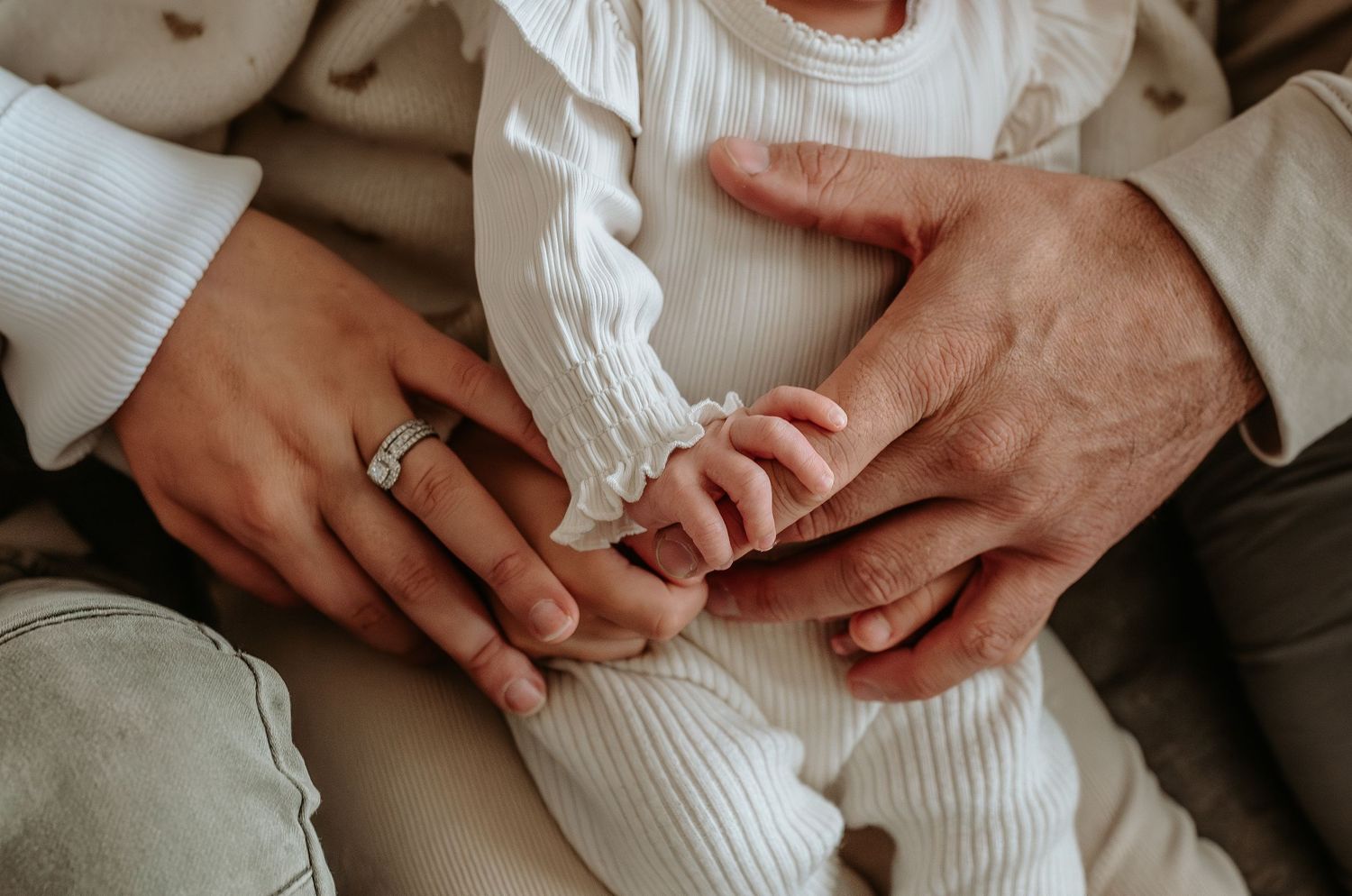 Close-up of hands and tender family interactions on grey couch.